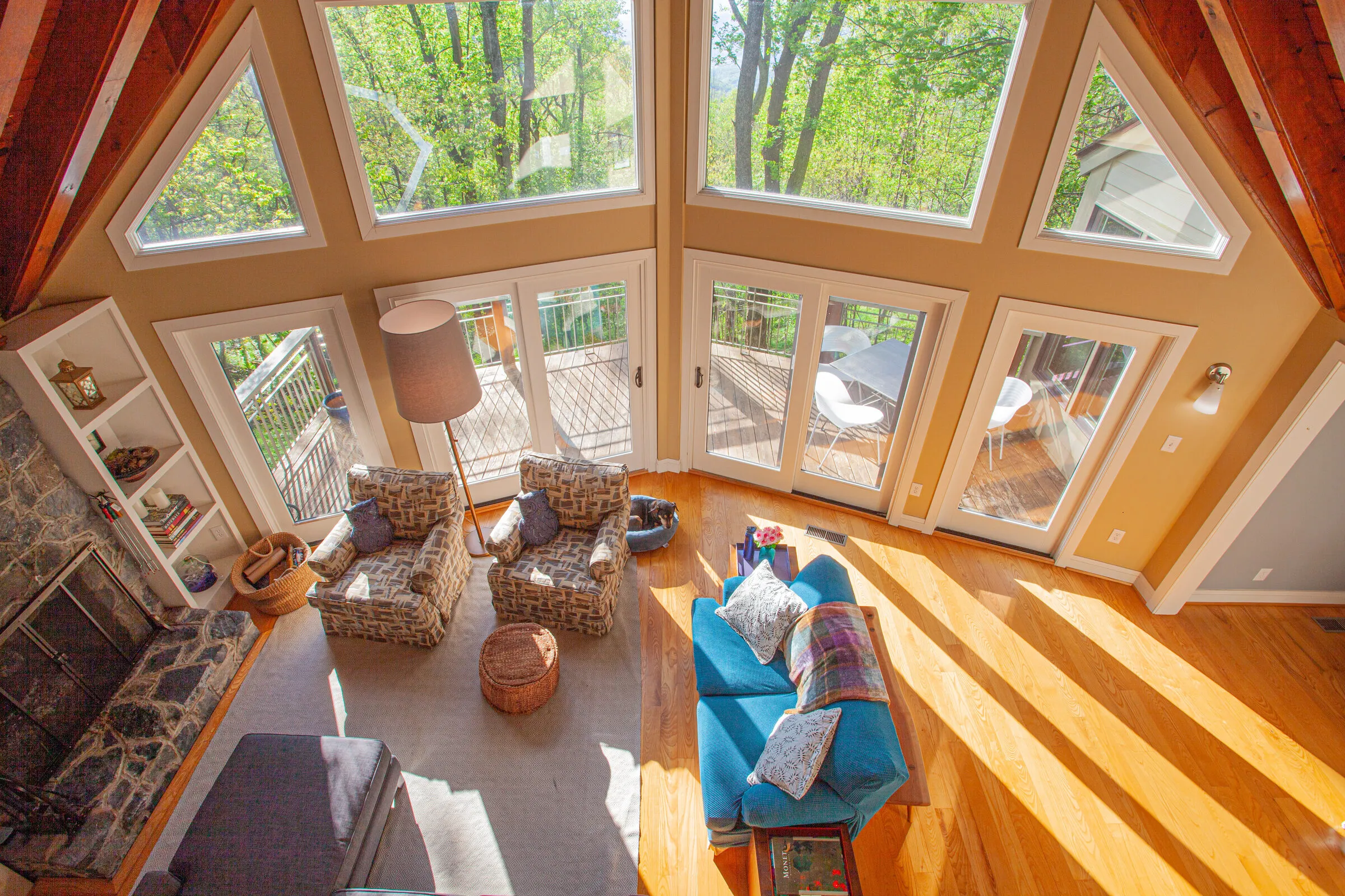 A-frame great room with floor-to-ceiling windows looking into the trees