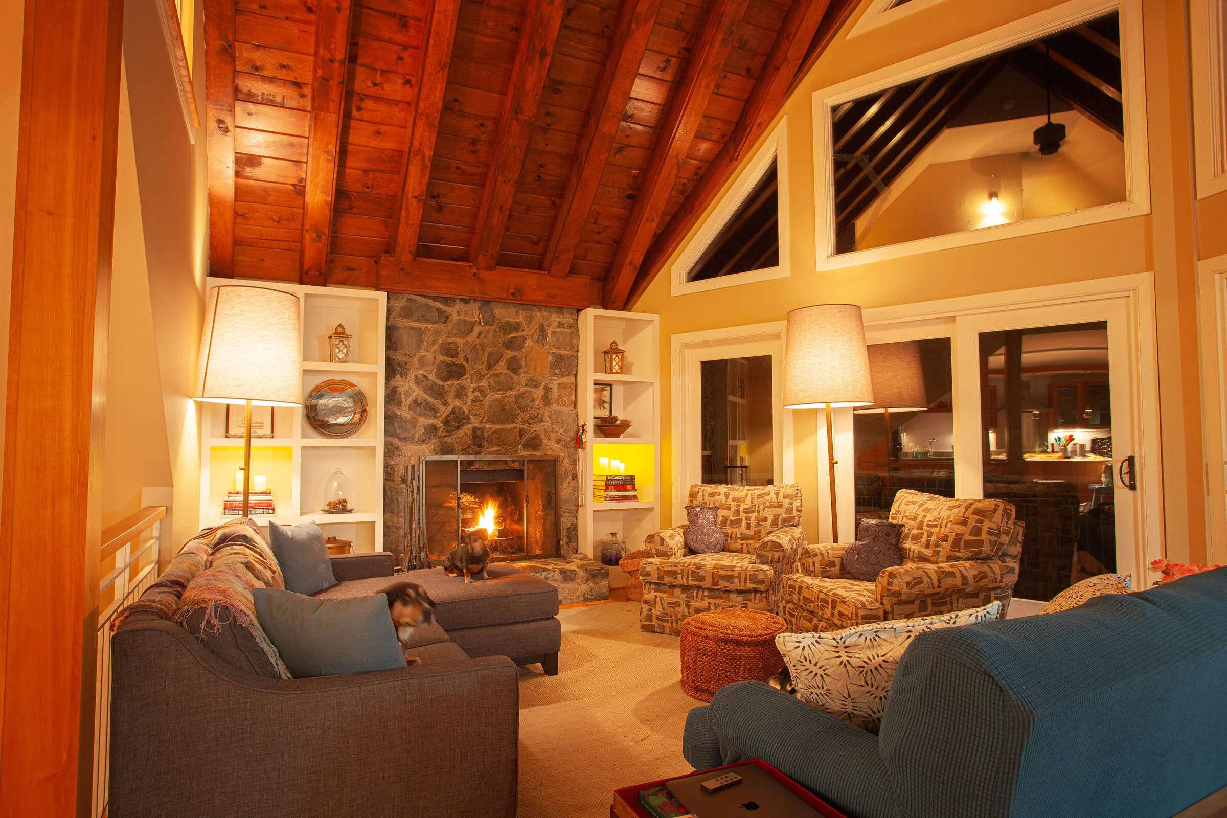 Great room at dusk with lamps lit and the fireplace going