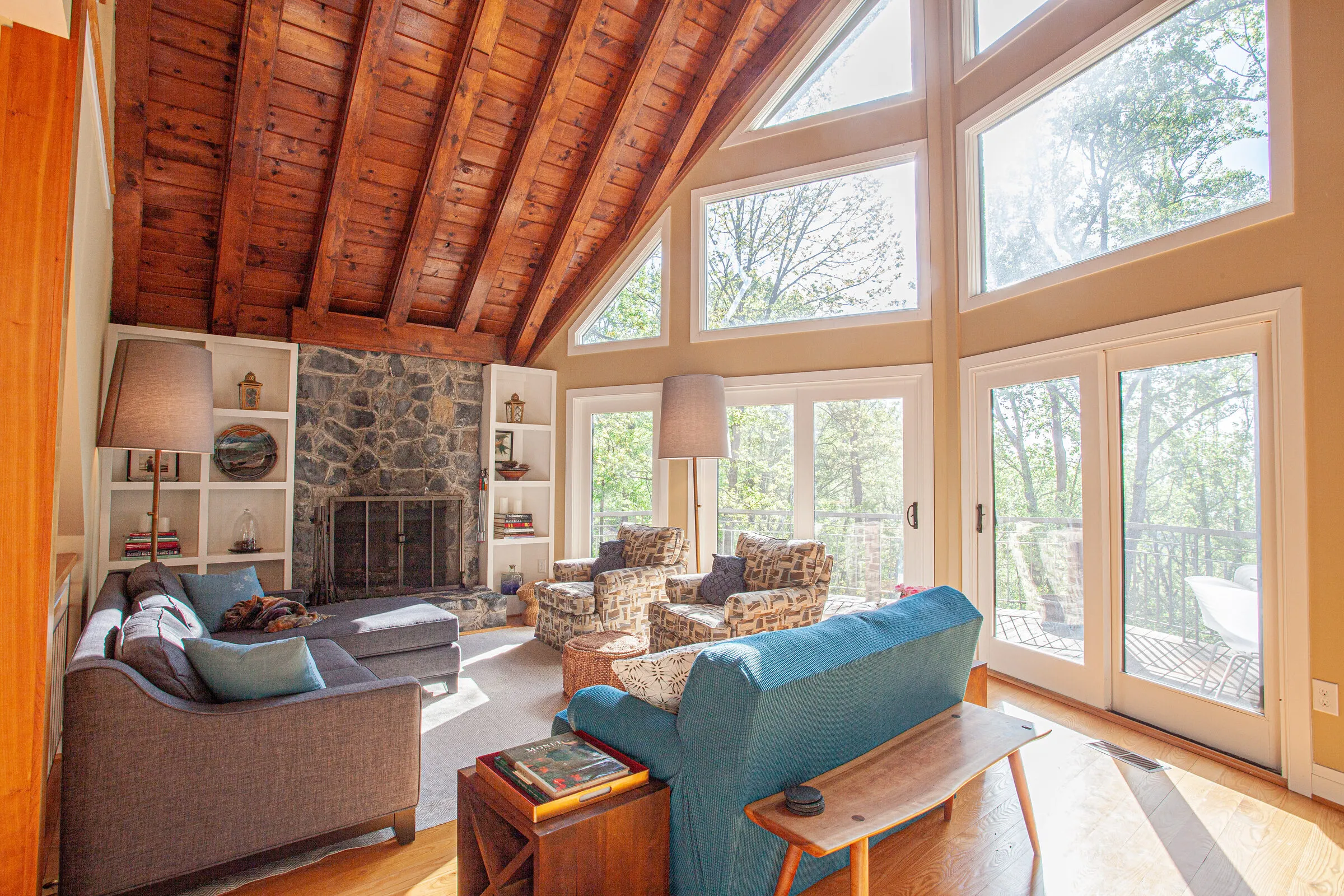 Great room with A-frame windows, blue sofas, and stone fireplace
